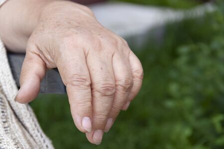 the hand of an elderly woman on the arm of a chairの写真素材