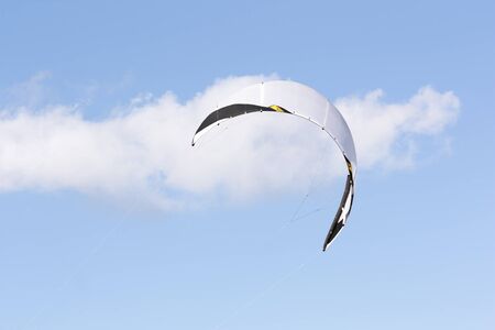 White kiteboarding kite on the background of a white cloud in the blue skyの写真素材