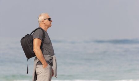 Portrait of a man with a backpack on the background of the seaの写真素材