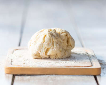 Raw dough lies on a cutting board on a plank tableの写真素材