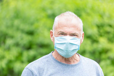 A man with a protective mask looking directly at the camera against a nature backgroundの写真素材