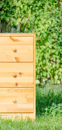 Part of a pine chest of drawers against a green lawnの写真素材