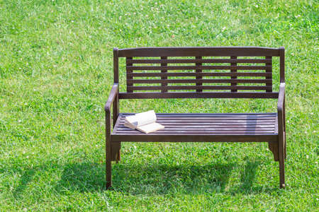 Shabby wooden bench with an open book on a green lawn top viewの写真素材