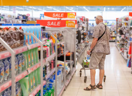 A man with a protective mask chooses a product in a department storeの写真素材