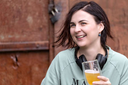 A girl wearing headphones with a glass of beer in her hand