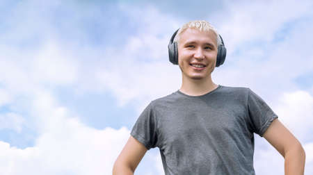 Guy with headphones standing against the sky