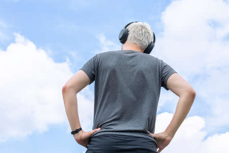 Guy with headphones standing against the sky