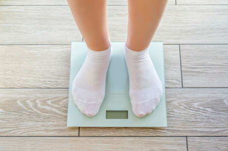 Women's feet in white socks stand on electronic floor scalesの写真素材