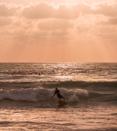 A picturesque seascape with a surfer gliding on a wave at sunsetの写真素材