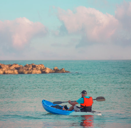 A kayaker in a life jacket paddles a kayak on the seaの写真素材