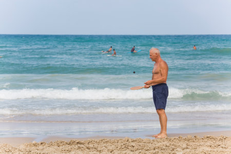A mature man trains with a ball before playing matkot on the beach.の写真素材