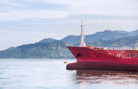 The bow of a red ship against the background of mountains and the seaの写真素材
