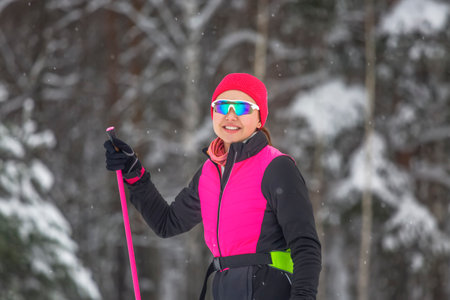 Portrait of a smiling girl skiers dressed in sporty clothes with ski poles in her handの写真素材