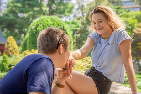 The guy kisses the hand of a smiling happy girl. She has an engagement ring on her finger. A sunny...