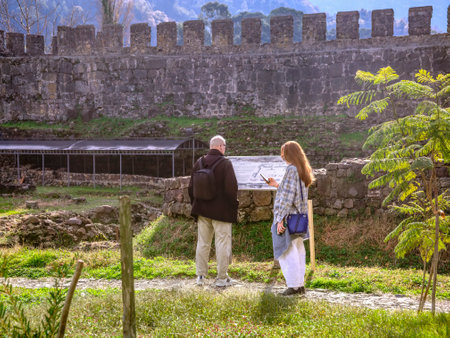 A man and a woman stand at an information stand at the archaeological site of an ancient fortressの写真素材