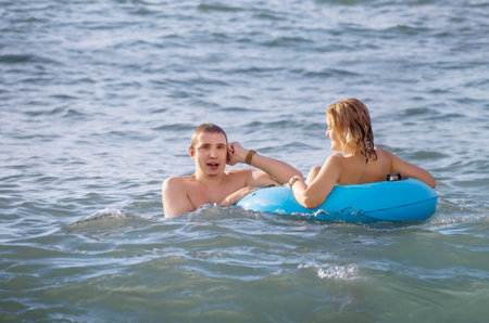 A young couple swims in the sea with an inflatable circleの写真素材