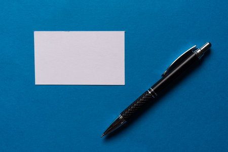 A note and ballpoint pen on a blue backgroundの写真素材