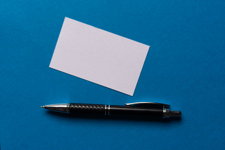 A note and ballpoint pen on a blue backgroundの写真素材