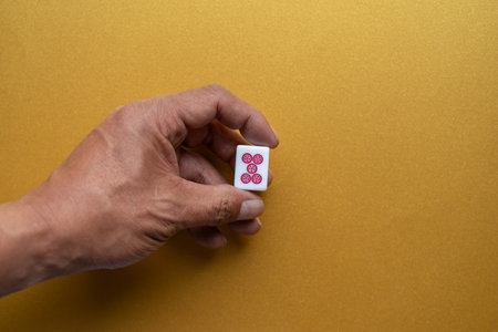 Mahjong tiles held in hand on a golden backgroundの写真素材