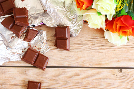 An arrangement of broken milk chocolate blocks, shot overhead on a rustic worn wooden background, using natural daylight.の写真素材