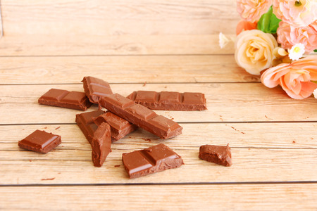 An arrangement of broken milk chocolate blocks, shot overhead on a rustic worn wooden background,...