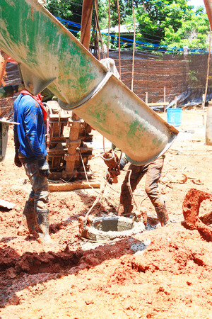 A construction worker works with a concrete truck and spreads concrete around to create a slab for the floor of a new building.のeditorial素材