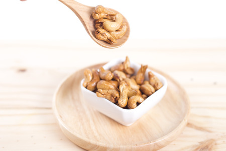 cashew nuts on a rustic wooden scoop against grunge wood background.