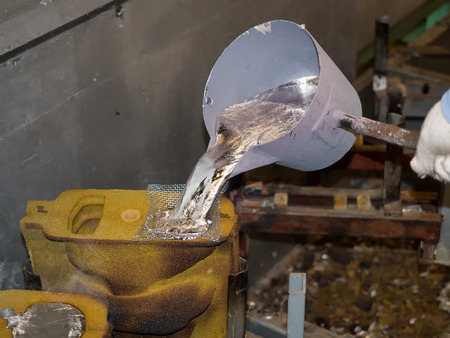 operator pouring aluminum automotive parts by pouring ladleの写真素材