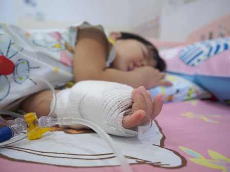 little girl on a drip receiving a saline solution in hospitalの写真素材