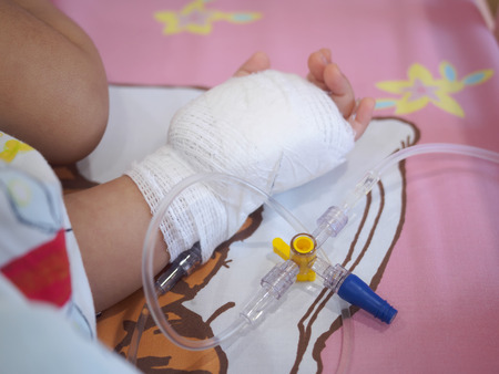 little girl on a drip receiving a saline solution in hospitalの写真素材