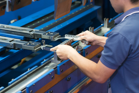 operator bending metal sheet by sheet bending machine. High pressure of hydraulic sheet metal  bending machine. jig and die for vari angle bending shape, accuracy punch and die manufacturing, electronic and automative part manufacturingの写真素材