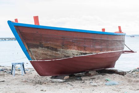 Old wooden boat on the shore waiting for repair.の写真素材