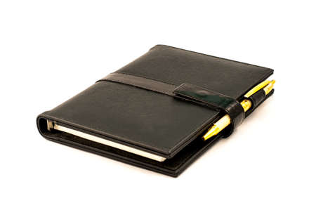 Black note book with ballpoint pen on white backgroundの写真素材