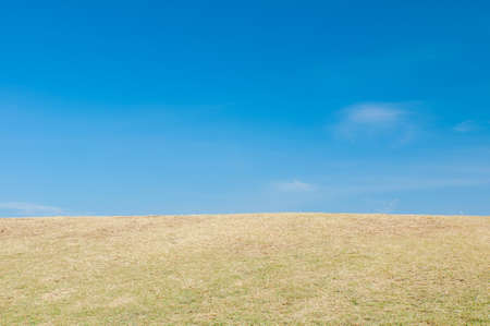 Green sloping  meadows and clouds with blue skyの写真素材