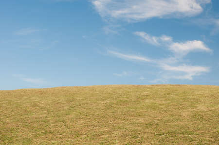 Green sloping  meadows and clouds with blue skyの写真素材