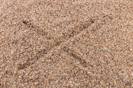Character X of the alphabet writing on the sandの写真素材