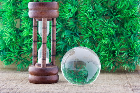 Wood hourglass countdown start and the globe on green grass backgroundの写真素材