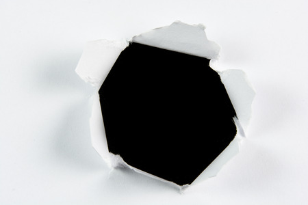 Breakthrough torn big black hole in white paper isolated background