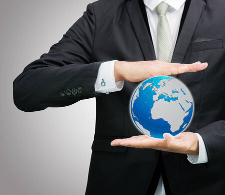 Businessman standing posture hand holding Earth icon isolated on over gray backgroundの写真素材