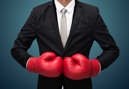 Businessman standing posture in boxing gloves isolated on over blue backgroundの写真素材