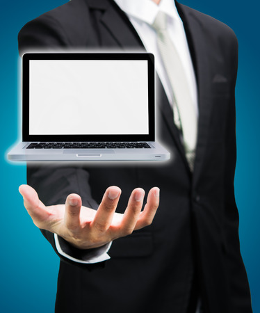 Businessman standing posture hand hold laptop isolated on over blue backgroundの写真素材