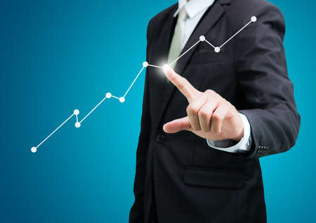 Businessman standing posture hand touch graph finance isolated on over blue backgroundの写真素材