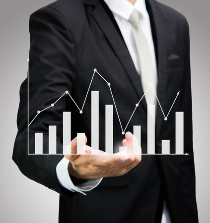 Businessman standing posture hand holding graph finance isolated on over gray backgroundの写真素材