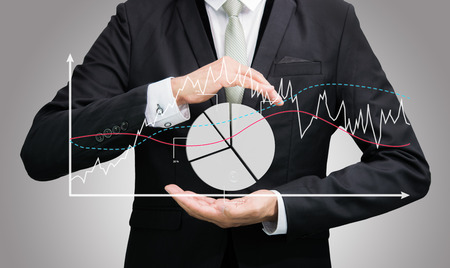 Businessman standing posture hand holding graph finance isolated on over gray backgroundの写真素材