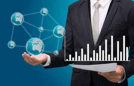 Businessman standing posture hand hold earth showing graph isolated on blue backgroundの写真素材