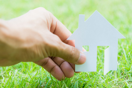 concept image of make house with white paper cut on green grass backgroundの写真素材