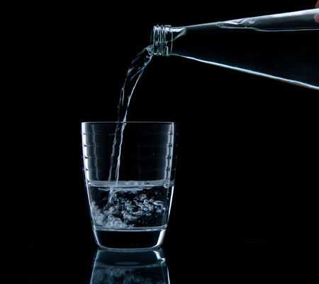 Pouring water on glass on over black backgroundの写真素材