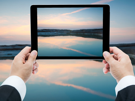 Businessman hands holding tablet taking pictures Sam Phan Bok rock canyon beside Khong riverの写真素材