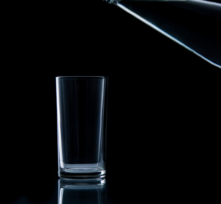 Pouring water on glass on over black backgroundの写真素材