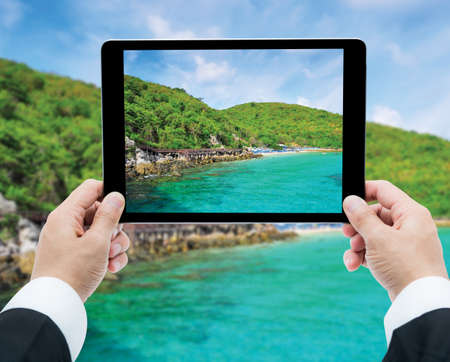 Businessman hands tablet taking pictures beach and sea on cloud